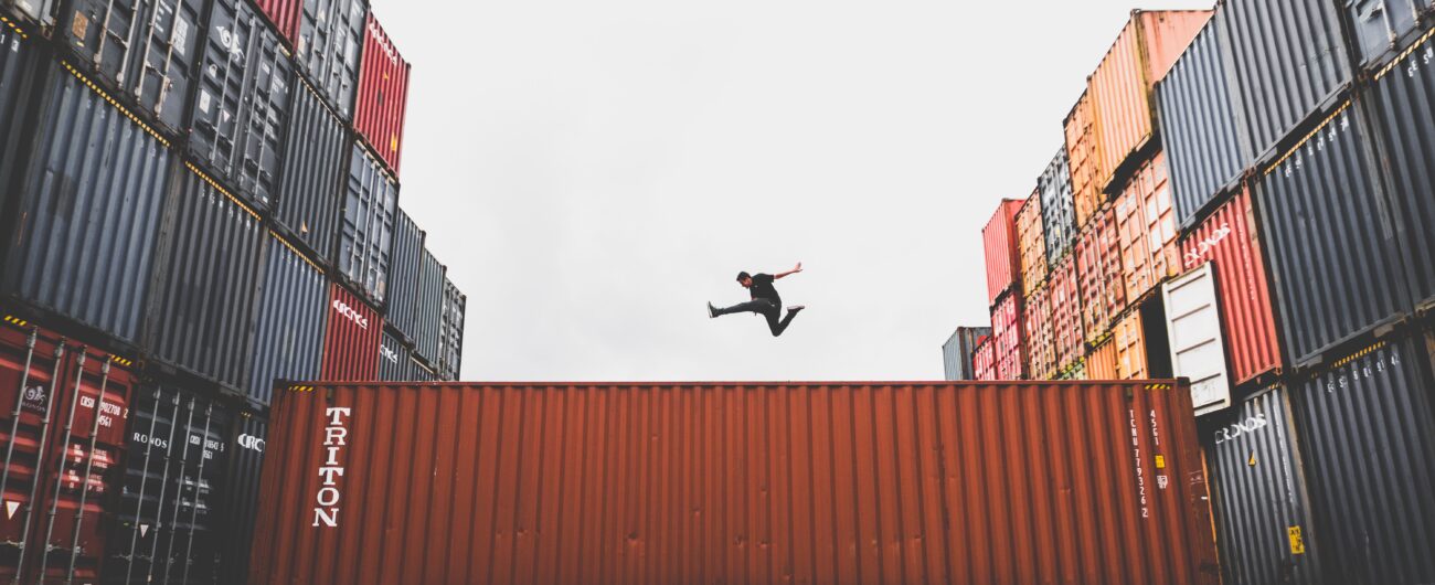 man jumps over shipping container