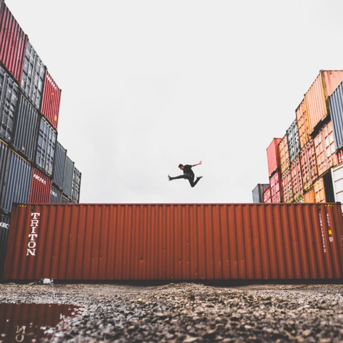 man jumps over shipping container